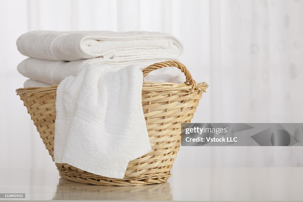 Studio shot of stack of white towels in Wicker Basket