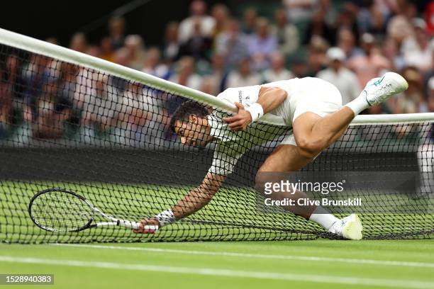 Novak Djokovic of Serbia falls over the net against Hubert Hurkacz of Poland in the Men's Singles fourth round match during day seven of The...