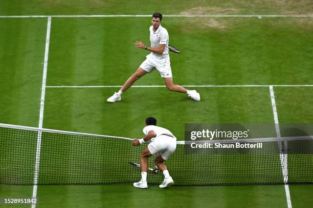 Novak Djokovic of Serbia falls over the net against Hubert Hurkacz of Poland in the Men's Singles fourth round match during day seven of The...