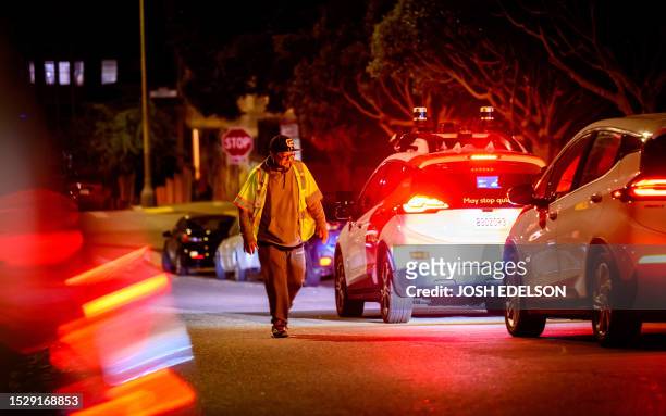 Cruise technician removes a cone from the hood of a disabled self-driving robotaxi in San Francisco, California on July 11, 2023. Members of...