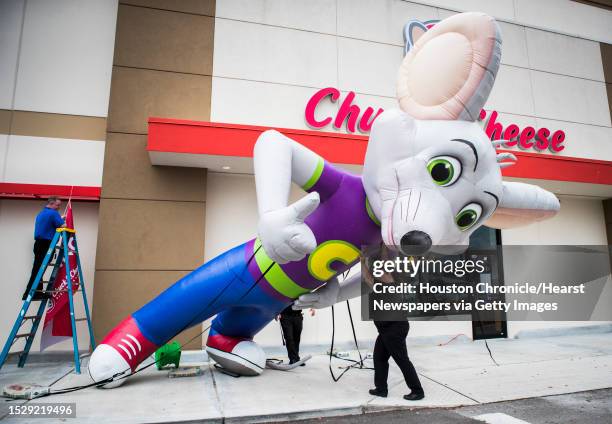 Yvette Zamarripa and other Chuck E. Cheese's employees get an inflatable Chuck E. Cheese mouse mascot ready for the grand opening of the family...