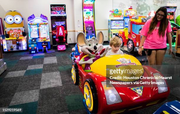 Scotty Birdwell accompanied by his mother Samantha Luce pretends to drive a car at the new Chuck E. Cheese's game room during the grand opening,...