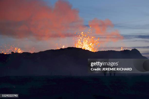 This picture taken on July 13, 2023 shows people watch a volcanic eruption at Litli Hrutur, south-west of Reykjavik in Iceland. A volcano erupted...