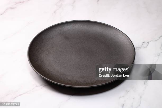 empty black ceramic plate on marble table - empty plate stock pictures, royalty-free photos & images