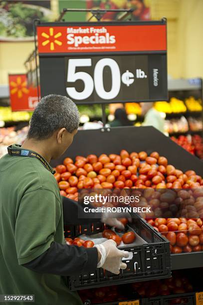 Walmart sales associate restock fresh tomatoes during the Grand Opening of the new Walmart Neighborhood Market in Panorama City, California, a...