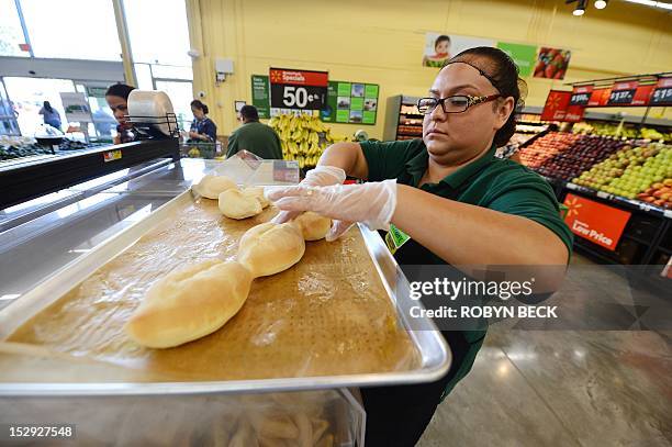Walmart bakery worker puts hot, freshly baked rolls in display bins during the Grand Opening of the new Walmart Neighborhood Market in Panorama City,...