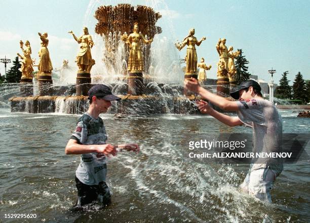Russian youths playu in the Soviet-era Fountain of the Nations' Friendship at the All-Russian Exhibition Center in Moscow 07 June 1999 as the...