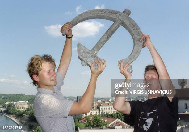 Two young Lithuanians display a hammer and sickle, the communist emblem which was removed from a facade of a building 03 September 1991 in Vilnius as...
