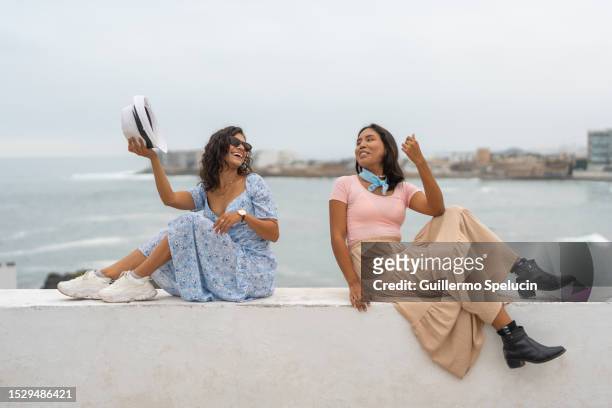 two happy friends sitting on a promenade - lima perú stock pictures, royalty-free photos & images