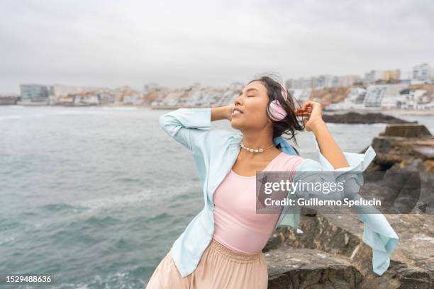 cool woman listening to music next to the sea - san bartolo peru stock pictures, royalty-free photos & images