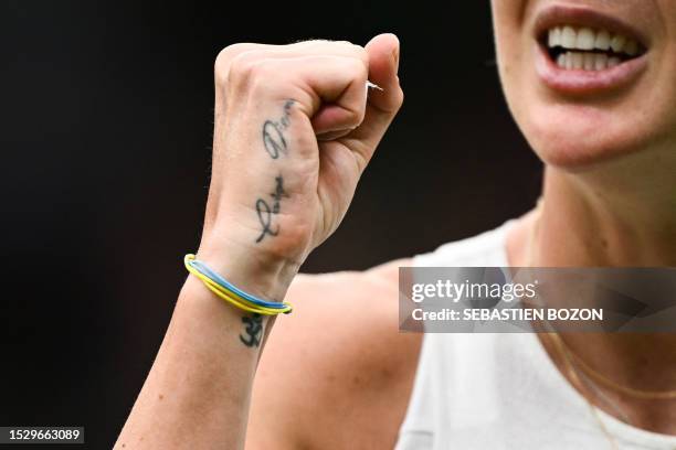 Tattoo reading "Carpe Diem" and a bracelet with the colour of Ukraine are pictured on the hand of Ukraine's Elina Svitolina celebrates winning a...