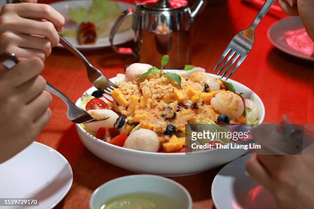 close up image of friends sharing and enjoying a bowl of colorful salad together. - salad server stock pictures, royalty-free photos & images