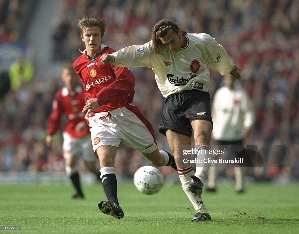 Patrik Berger of Liverpool (right) kicks the ball ahead of David Beckham of Manchester United
