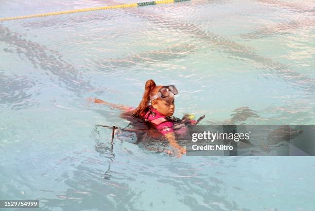 View of American rapper Lisa 'Left Eye' Lopes as she floats in a swimming pool on the set of TLC's 'Not Tonight' music shoot, West Palm Beach,...