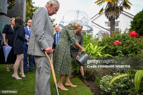 Britain's King Charles III and Britain's Queen Camilla plant and water a shrub as they takes a tour of the Barbara Hepworth Museum and Sculpture...