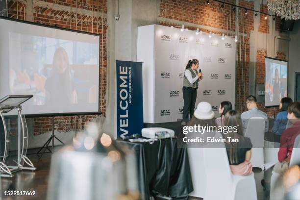 asian chinese young female speaker presenting on stage with video conference call on projector screen - zoom participant stock pictures, royalty-free photos & images