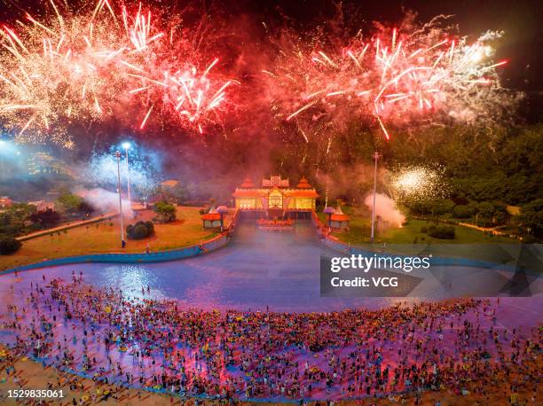 Fireworks explode as people cool off at a water park during a hot summer day on July 8, 2023 in Nanjing, Jiangsu Province of China.