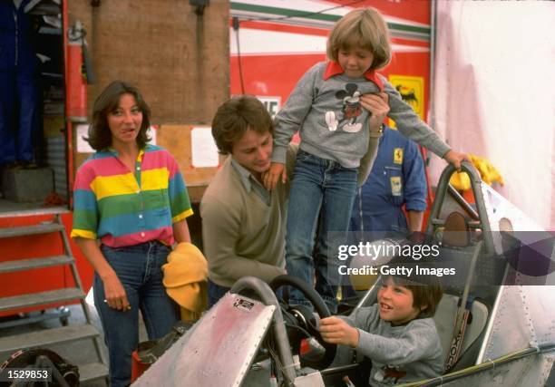 Gilles Villeneuve puts son Jacques at the Controls of his Ferrari Formula One racing car whilst being pictured with his family in the Ferrari paddock...