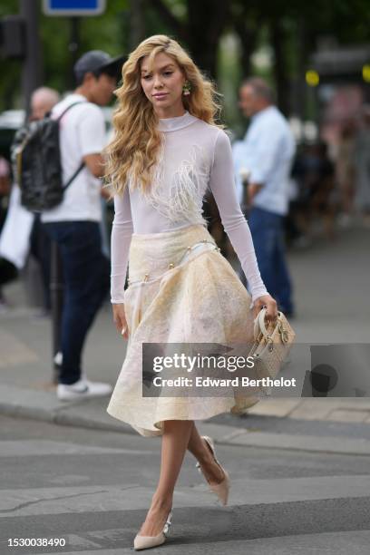 Guest wears pink / green / gold flower pattern pendant earrings, a white tulle high neck / long sleeves body with embroidered white feathers details,...