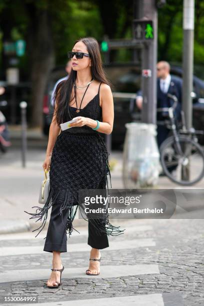 Guest wears black squared futurist sunglasses from Celine, a gold necklace, a rhinestones necklace, a black embossed ruffled V-neck / tank-top /...