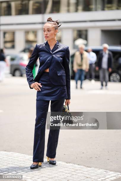 Guest wears a gold logo earring from Fendi, diamonds earrings a navy blue blazer jacket from Fendi, a matching navy blue silk suit pants, a black and...