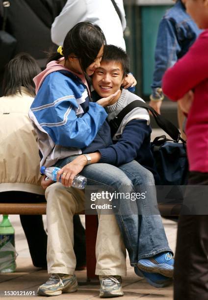 Young Chinese couple hug on a bench as thousands of shoppers gather outside a shopping complex in Beijing 02 October 2003. The National Day holiday...