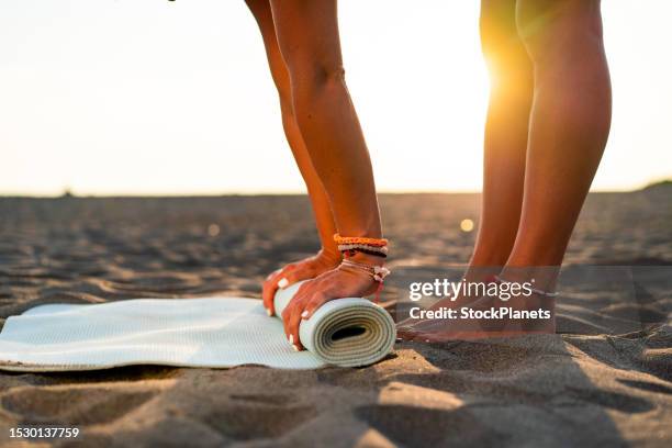 unrecognizable woman rolling out yoga mat - yoga mat stock pictures, royalty-free photos & images