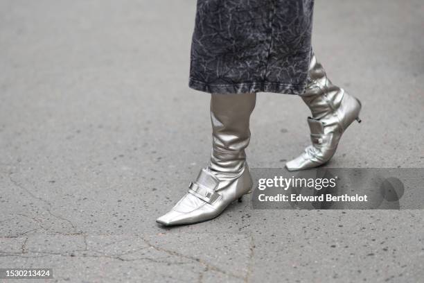 Guest wears a gray faded denim midi skirt, a silver shiny leather pointed / micro heels knees boots / high boot, outside Alexandre Vauthier, during...