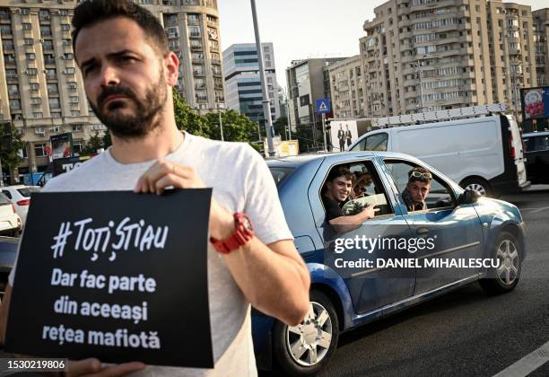 Protester holds a sign reading "They all knew - But they're the same Mafia" during a protest against the ruling parties coalition, in Bucharest, on...