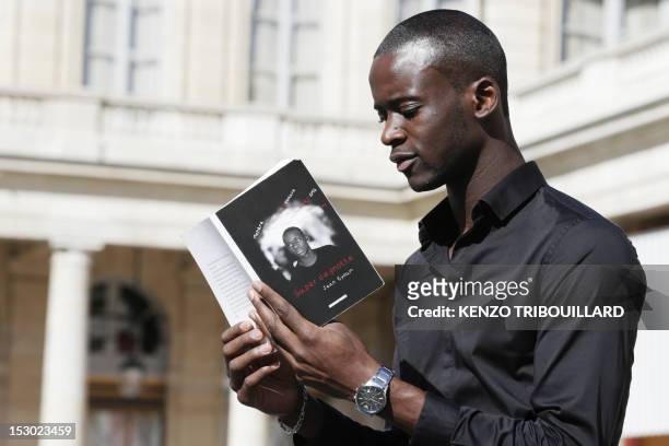 French Cameroonian-born student Jean Eyoum poses with his book on September 29, 2012 in Paris. Eyoum wrote "super cagnotte" a street-talk version of...