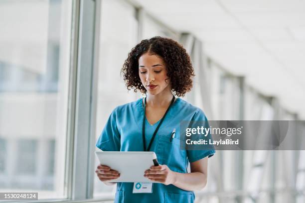 female nurse looking at digital tablet beside window in hospital - digital devices beside each other bildbanksfoton och bilder