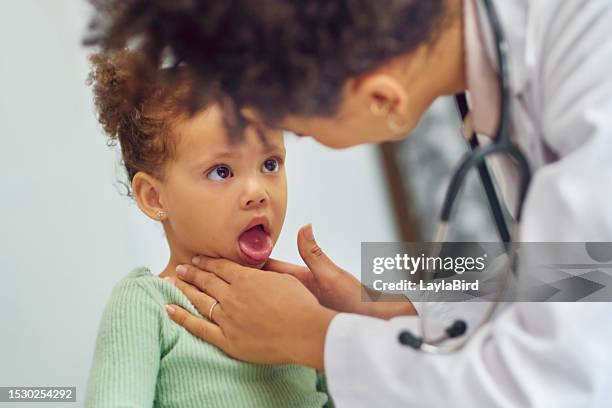 close-up of little girl sticking out tongue for female doctor in clinic - girl tongue doctor stockfoto's en -beelden