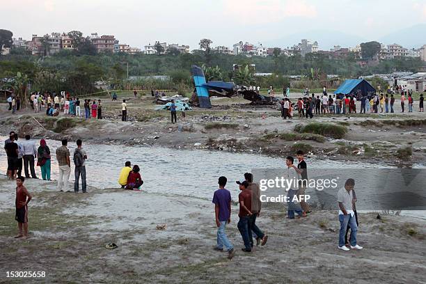 The mangled tail section of the crashed Sita Air Dornier Do 228 aircraft is seen as bystanders look on in Manohara, Bhaktapur on the outskirts of...