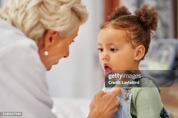 close-up of little girl sticking out tongue for pediatrician in clinic - girl tongue doctor stockfoto's en -beelden