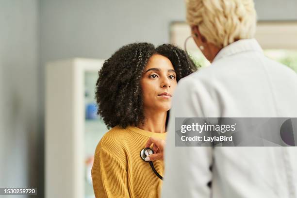 female patient looking at doctor examining her chest in clinic - cuidados de saúde primários imagens e fotografias de stock