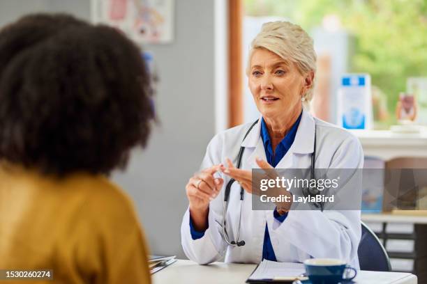female doctor giving advice to patient in clinic - een dag uit het leven serie stockfoto's en -beelden