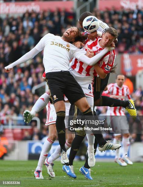 Michu and Ashley Williams of Swansea City squeeze out Robert Huth of Stoke City during the Barclays Premier League match at the Britannia Stadium on...