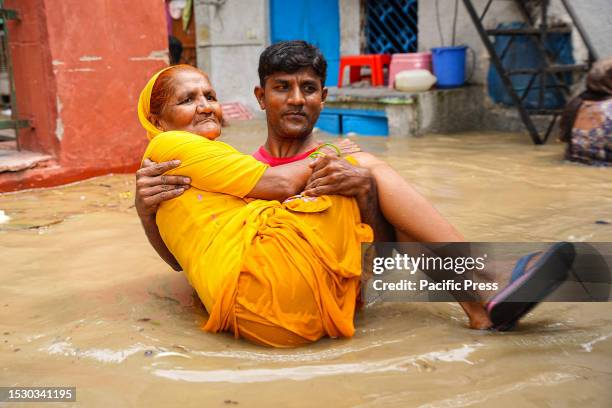 Man rescues an old lady after Yamuna River overflowed due to heavy monsoon rainfall.