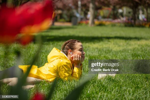 junge frau liest ein buch auf dem gras. - auf dem bauch liegen stock-fotos und bilder