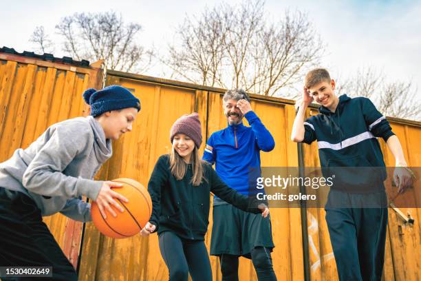 familie spielen basketball auf hinterhof im freien - 11 11 road stock-fotos und bilder