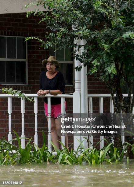 Woman watches as neighbors evacuate their flooded home in the Lochshire neighborhood Friday, Sept. 20 in Huffman, Texas. The Luce Bayou overflowed...