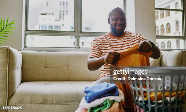 un jeune homme assis et pliant son linge. photo d’archives, espace de copie - lessive photos et images de collection