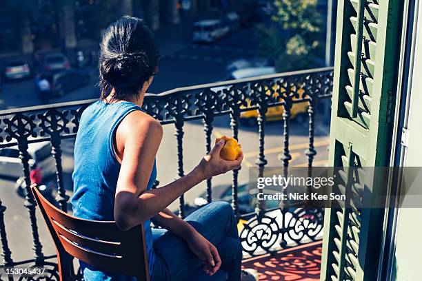 woman sitting on balcony - balkon essen stock-fotos und bilder