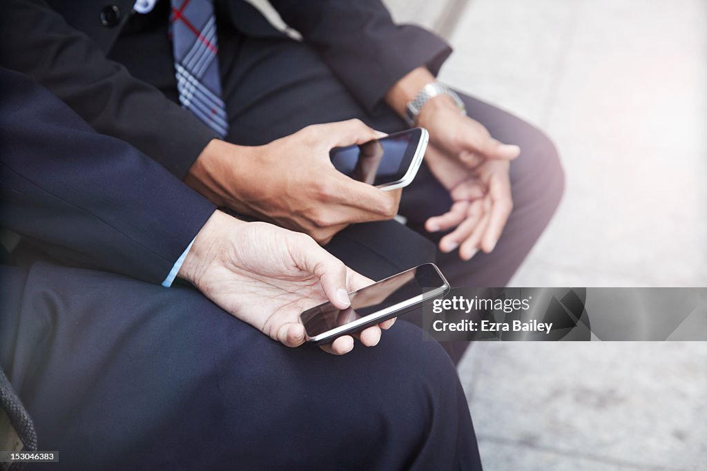 Two businessmen with phones outside