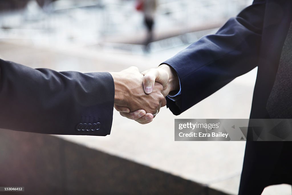 Businessmen shaking hands outside.