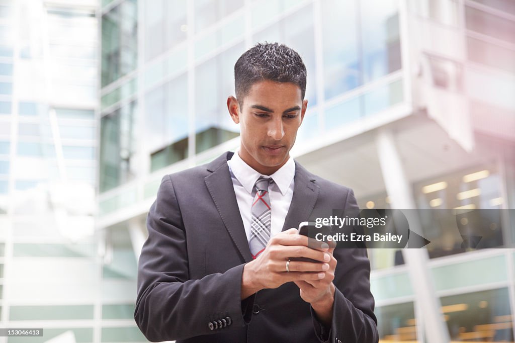 Young businessman using his phone outside.