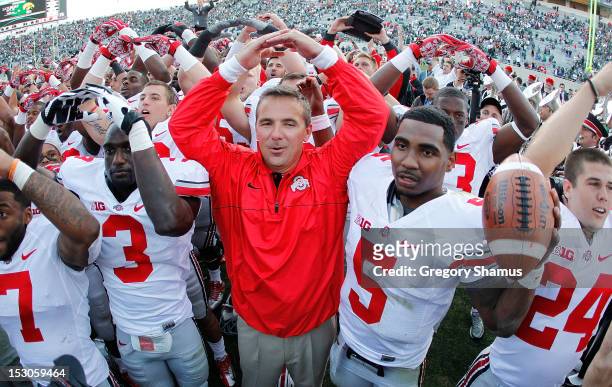 Head coach Urban Meyer of the Ohio State Buckeyes celebrates with his players after beating the Michigan State Spartans 17-16 at Spartan Stadium on...