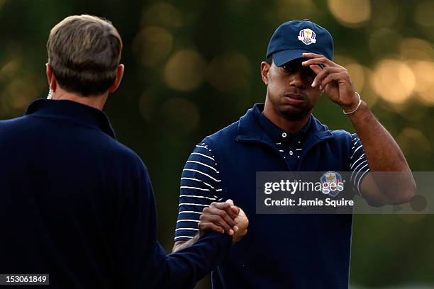Team captain Davis Love III greets Tiger Woods on the 18th green during day two of the Afternoon Four-Ball Matches for The 39th Ryder Cup at Medinah...