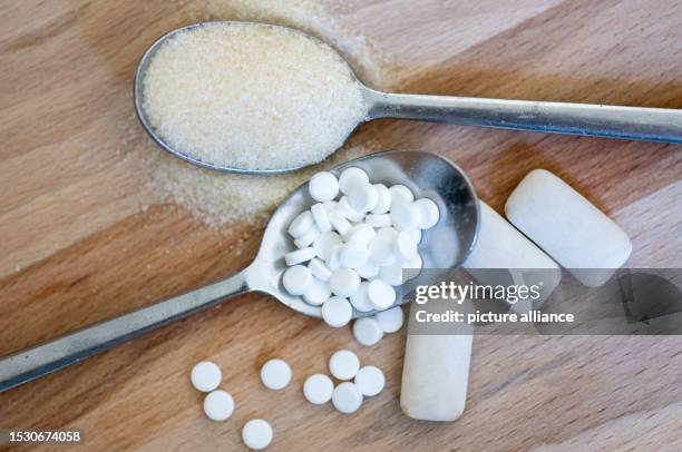 July 2023, Saxony, Leipzig: A spoonful of sweetener tablets is next to a spoonful of sugar and gum with sweeteners. Photo: Hendrik Schmidt/dpa
