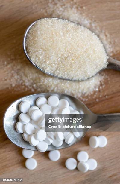 July 2023, Saxony, Leipzig: A spoonful of sweetener tablets lies next to a spoonful of sugar. A sweetener often used in soft drinks, yogurt and...